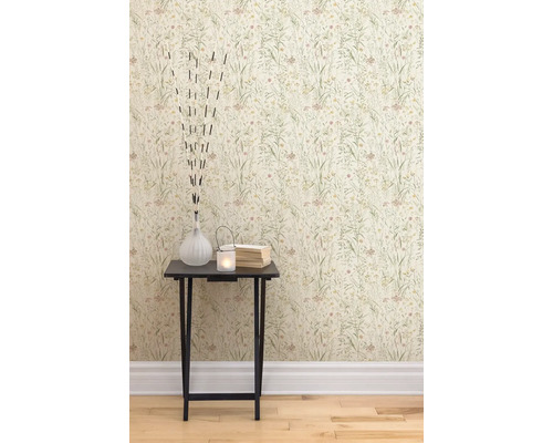 Une vue rapprochée d''un mur avec du papier peint à fleurs et une table d''appoint avec des objets décoratifs tels qu''un vase, une bougie chauffe-plat et des livres.