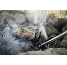 Steak auf Grillrost über offenem Feuerstelle mit Steinen.