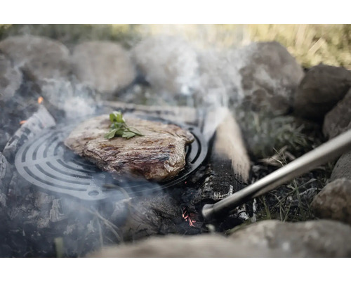 Steak sur une grille de cuisson au-dessus d''un foyer ouvert avec des pierres.