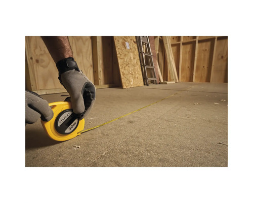 Une personne mesure une pièce en bois à l''aide d''un mètre à ruban de 30 mètres de Stanley.