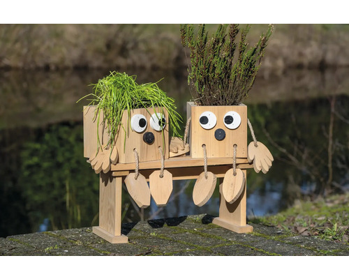 Dekorative Pflanzgefäße in Form von Figuren auf einer Bank, mit Pflanzen bepflanzt.