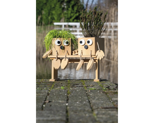 Zwei Pflanzkästen in Form von Figuren auf einer Bank mit Pflanzen