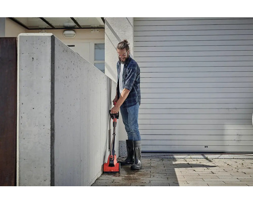 Mann reinigt eine Betonwand mit einer elektrischen Bürste im Außenbereich