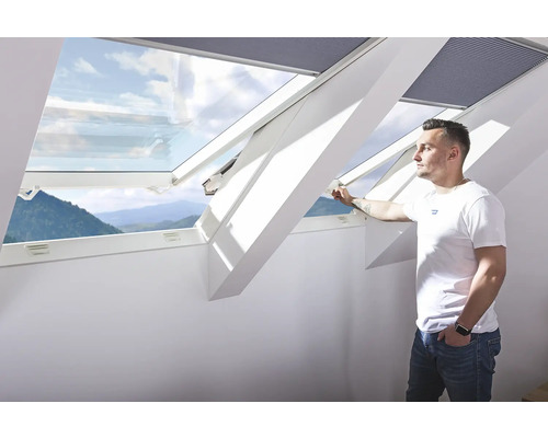 Mann öffnet ein Dachfenster mit Aussenansicht