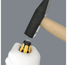 La main tient un protège-pouce sous le marteau