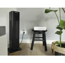 Scène d''intérieur avec un ventilateur colonne Clean Air, une minuterie, un tabouret avec des livres et une plante.
