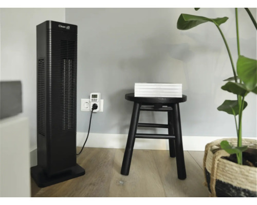 Scène d''intérieur avec un ventilateur colonne Clean Air, une minuterie, un tabouret avec des livres et une plante.