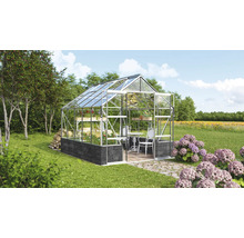 Serre avec étagères à plantes, table et chaises dans un jardin