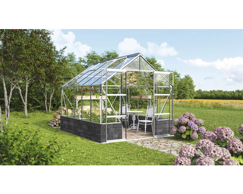 Serre avec étagères à plantes, table et chaises dans un jardin