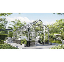 Serre avec parois en verre et cadre en métal dans le jardin.