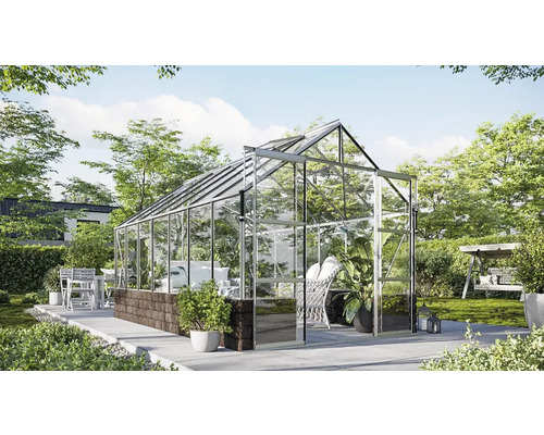Serre avec parois en verre et structure métallique dans le jardin