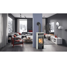 Heller Wohnraum mit Kaminofen, Couch und Blick auf eine verschneite Landschaft.