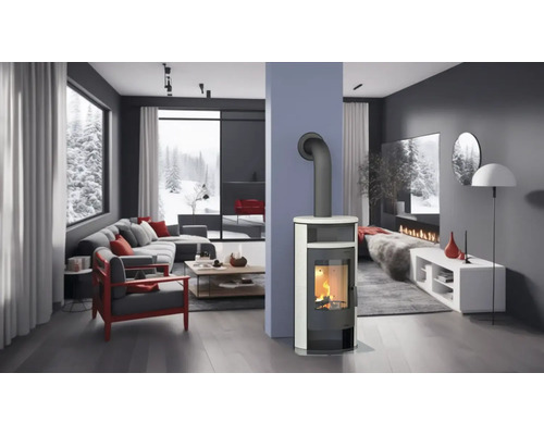 Heller Wohnraum mit Kaminofen, Couch und Blick auf eine verschneite Landschaft.