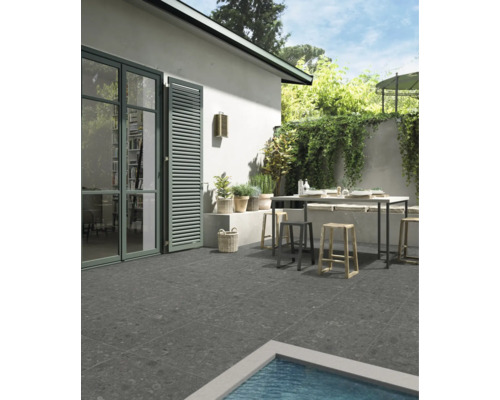 Terrasse mit Gartentisch und Stühlen, gefliest mit grauen Steinzeugfliesen.