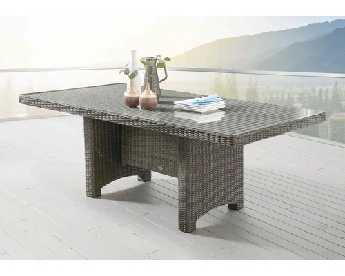 Table de jardin avec plateau en verre et aspect rotin sur une terrasse avec vue sur les montagnes
