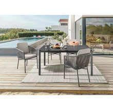 Gartenszene mit Esstisch, Stühlen und Teppich auf einer Terrasse neben einem Pool.