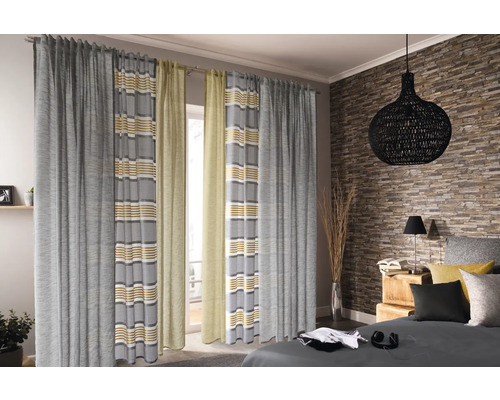 Blick in ein Schlafzimmer mit Gardinen vor dem Fenster