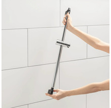 Une barre de douche est fixée à un mur carrelé.