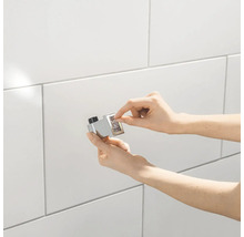 Installation d''un butoir de porte magnétique sur un mur carrelé.