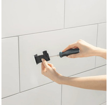 Installation d''un boîtier encastré avec un tournevis sur un mur carrelé.