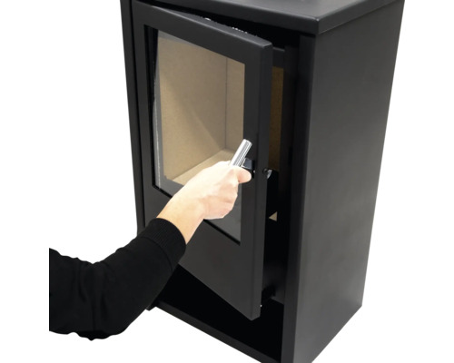 Poêle à bois avec porte ouverte et main sur la poignée