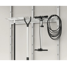 Outils de jardin tels que râteaux, pompe et tuyau suspendus à un panneau mural à outils.