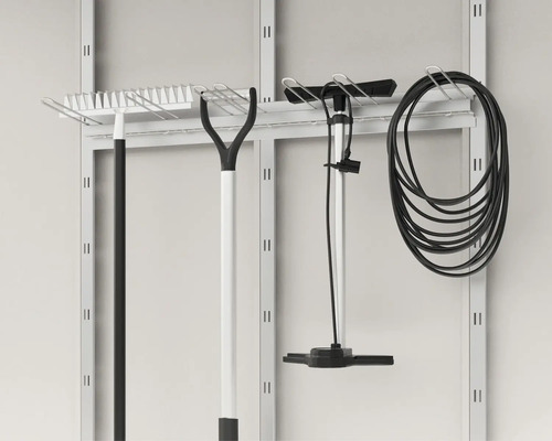 Outils de jardin tels que râteaux, pompe et tuyau suspendus à un panneau mural à outils.