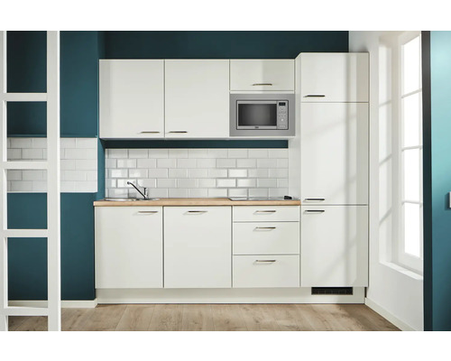 Helle Küche mit Spüle, Arbeitsplatte, Mikrowelle und weißen Schränken für einen organisierten Eindruck.