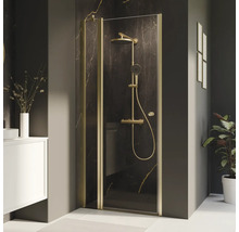 Paroi de douche avec cadre doré et robinetterie de douche dans une salle de bains.