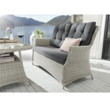 Scène avec canapé en rotin, table et décoration sur une terrasse avec vue sur la montagne