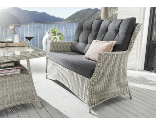 Scène avec canapé en rotin, table et décoration sur une terrasse avec vue sur la montagne