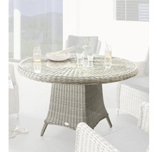 Scène de jardin avec table de jardin ronde en rotin avec plateau en verre et chaises