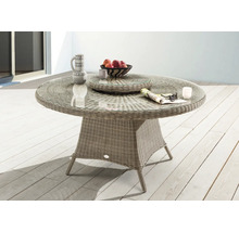 Table de jardin ronde avec plateau en verre et surface en rotin sur une terrasse