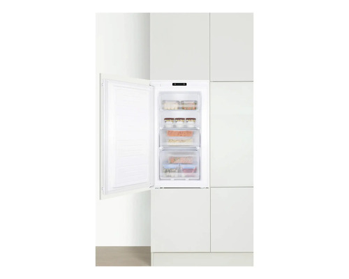 Congélateur intégré avec porte ouverte dans une cuisine blanche.