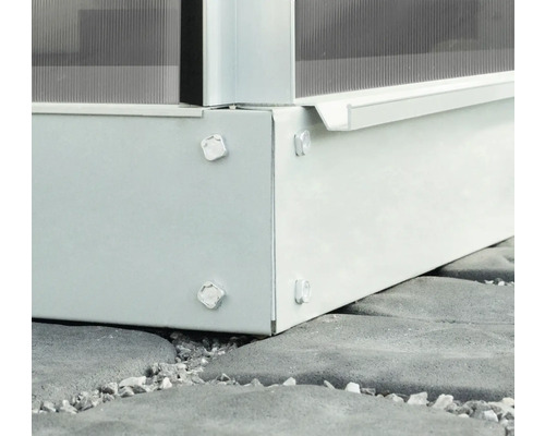 Vue détaillée d''une fondation de serre avec des vis sur un sol en pierre