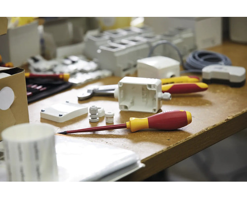 Photo d''outils et de matériaux d''électricien sur un établi, notamment des tournevis, des boîtiers et des presse-étoupes