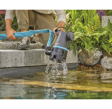 Eine Person entleert einen Gartenteich mit einer Gardena-Pumpe und einem Schlauch.