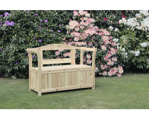 Banc de jardin avec malle à coussins bois 3 places naturel Banc de jardin en bois avec espace de rangement devant des buissons fleuris