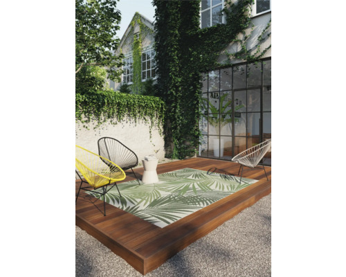 Terrasse mit Outdoor-Teppich, Stühlen und Beistelltisch vor einem mit Efeu bewachsenen Haus.
