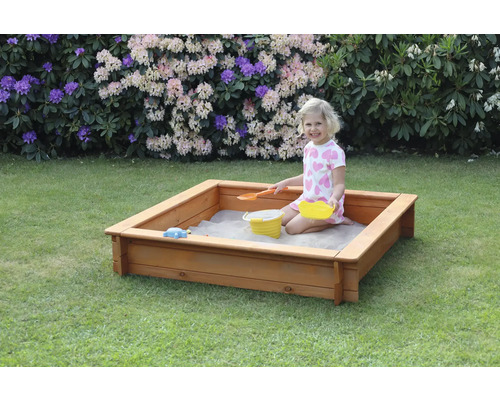 Quadratischer Sandkasten aus Holz mit spielendem Kind im Garten