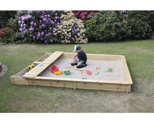 Bac à sable Yanick avec assise/coffre de rangement 225x253x21 cm naturel Un enfant joue dans un bac à sable en bois avec des jouets dans le jardin.