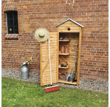 Armoire de jardin en bois avec outils de jardin devant un mur de briques