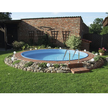 Heller Garten mit rundem Einbaupool, Ziegelsteineinfassung, Natursteinrand, Edelstahlleiter und Kugelleuchten auf Rasen vor einer Backsteinwand.