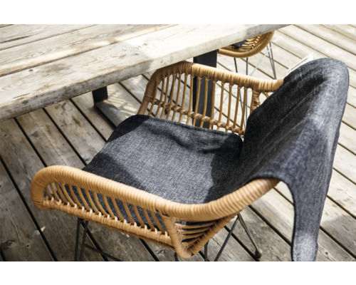 Gartenszene mit Rattan-Gartenstuhl und Sitzkissen unter Holztisch