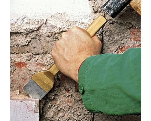 Handwerker arbeitet mit einem Hammer und einem Meißel an einer Mauer.
