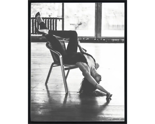 Photo en noir et blanc d''une femme assise à l''envers sur une chaise