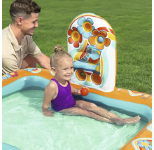 Kind sitzt in aufblasbarem Planschbecken mit Rollschuh Design, beobachtet von einem Mann