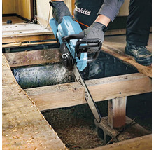 Artisan coupant une planche en bois avec une tronçonneuse sans fil. Logo Makita.
