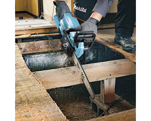 Artisan coupant une planche en bois avec une tronçonneuse sans fil. Logo Makita.