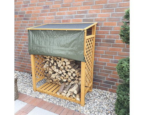 Holzlager mit Holz und Abdeckplane vor einer Ziegelwand